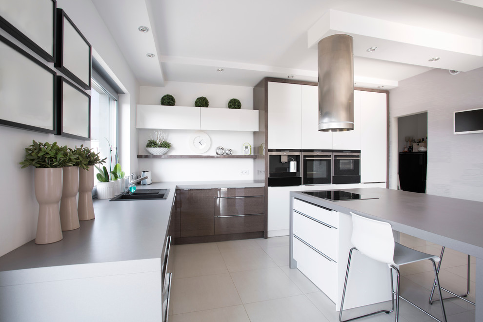 На фото: параллельная кухня в современном стиле с накладной мойкой, плоскими фасадами, белыми фасадами, черной техникой и островом с