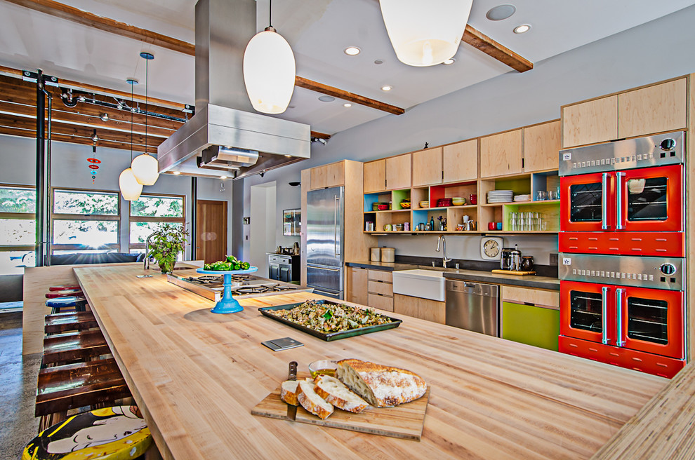 Industrial galley kitchen in Seattle with a belfast sink, wood worktops, open cabinets, light wood cabinets and coloured appliances.