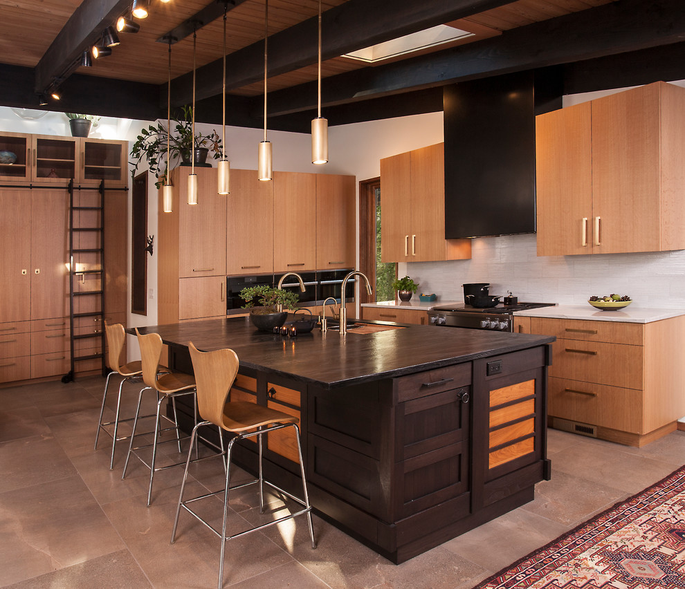 Photo of a large world-inspired single-wall kitchen/diner in Seattle with black worktops, a submerged sink, flat-panel cabinets, light wood cabinets, wood worktops, grey splashback, porcelain flooring, an island and grey floors.