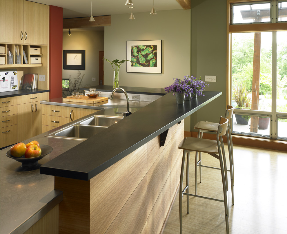 На фото: кухня в современном стиле с накладной мойкой, плоскими фасадами, светлыми деревянными фасадами и барной стойкой