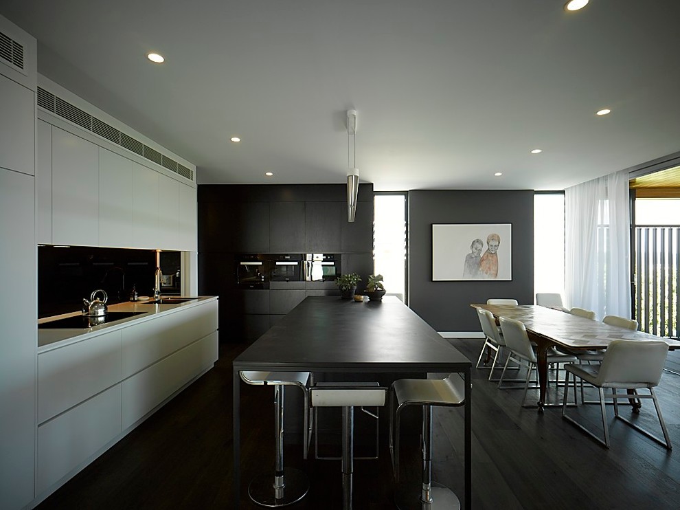 Inspiration for a large contemporary u-shaped open plan kitchen in Sydney with flat-panel cabinets, white cabinets, engineered stone countertops, black splashback, dark hardwood flooring, an island, black floors and black worktops.