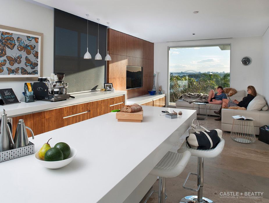 This is an example of a contemporary l-shaped open plan kitchen in New York with an island, flat-panel cabinets, medium wood cabinets, engineered stone countertops, black splashback, glass sheet splashback, stainless steel appliances, an integrated sink and travertine flooring.