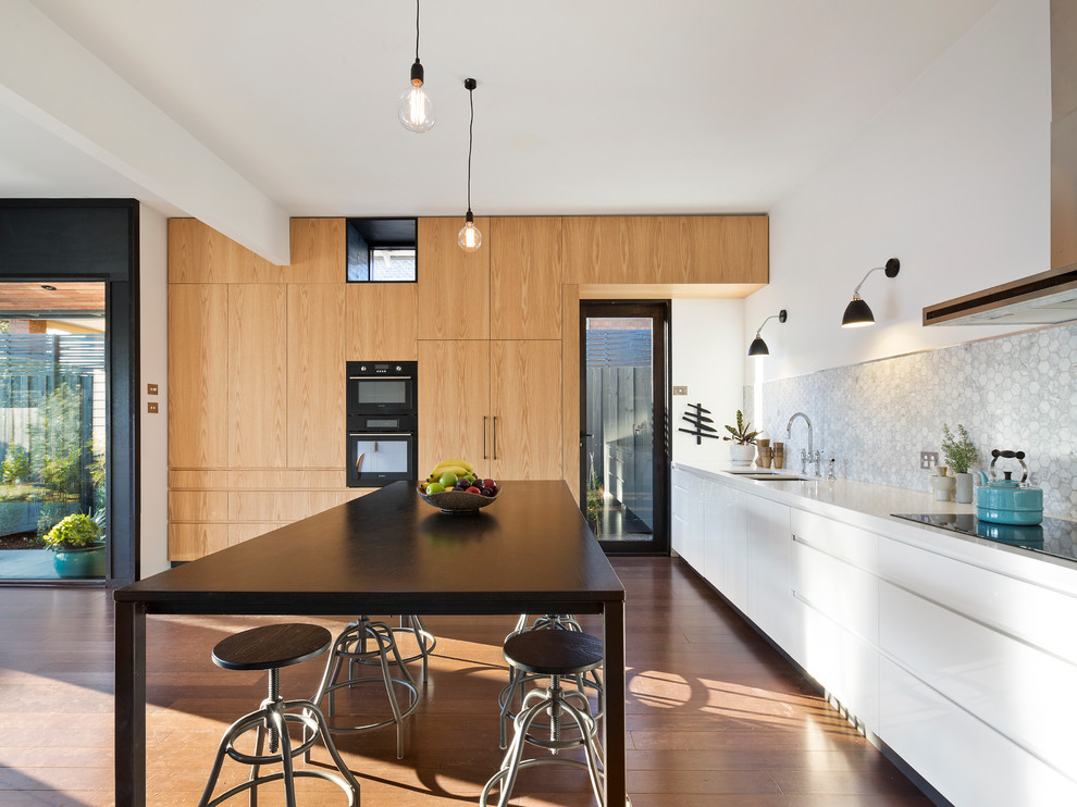 Moderne Küche mit Unterbauwaschbecken, flächenbündigen Schrankfronten, weißen Schränken, Küchenrückwand in Grau, braunem Holzboden und Kücheninsel in Melbourne