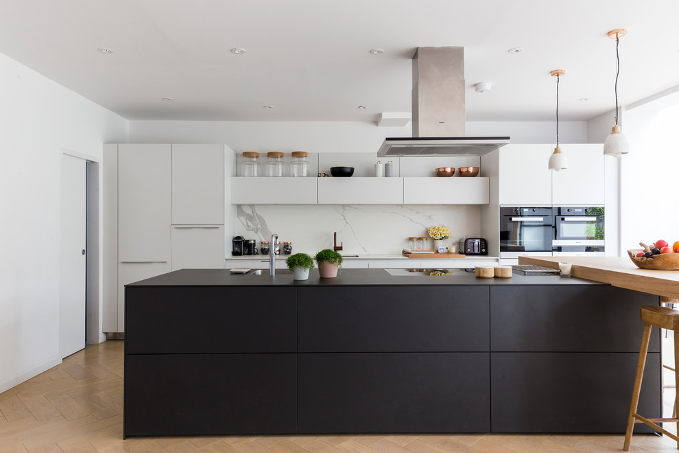 Design ideas for a large contemporary galley kitchen/diner in London with a submerged sink, flat-panel cabinets, white cabinets, white splashback and an island.