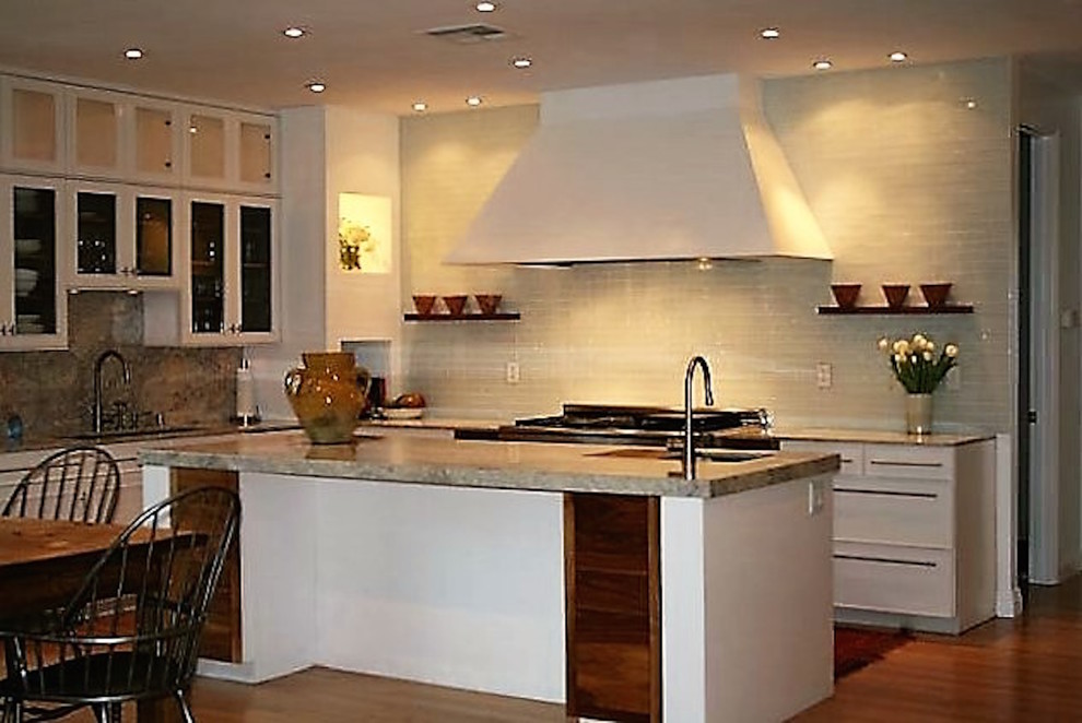 Bild på ett stort vintage kök, med en enkel diskho, luckor med infälld panel, vita skåp, granitbänkskiva, grönt stänkskydd, stänkskydd i glaskakel, integrerade vitvaror, mellanmörkt trägolv och en köksö