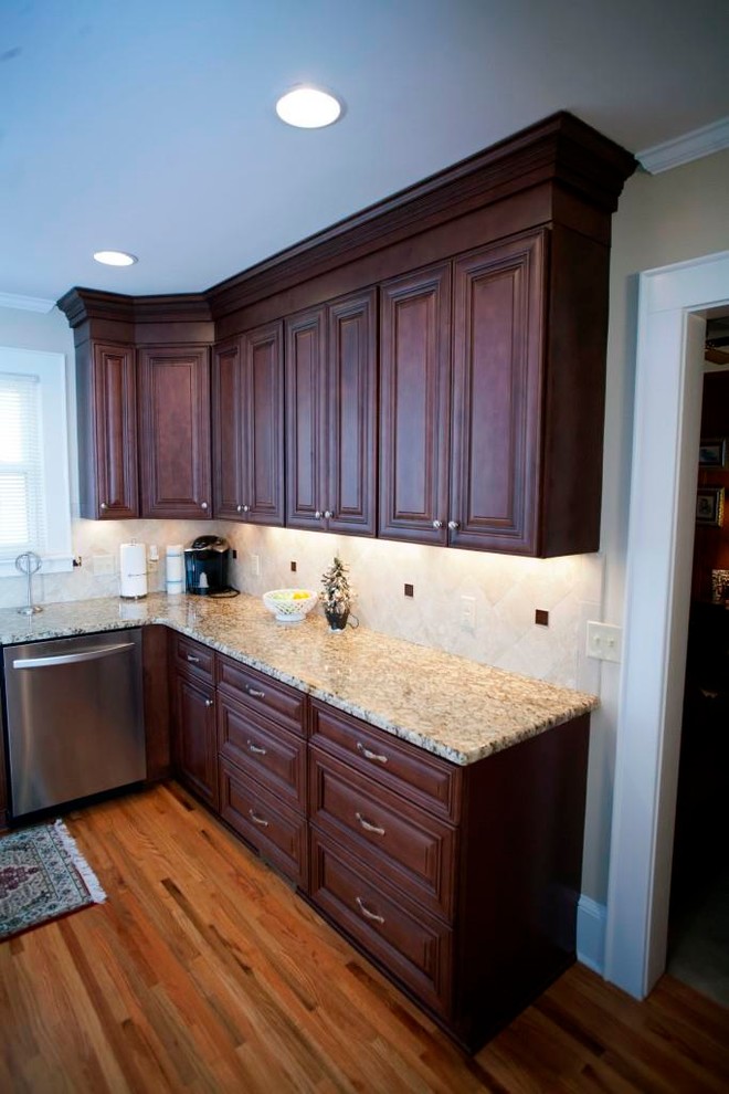 Example of a transitional u-shaped eat-in kitchen design in Charlotte with an undermount sink, raised-panel cabinets, dark wood cabinets, granite countertops, beige backsplash, subway tile backsplash and stainless steel appliances
