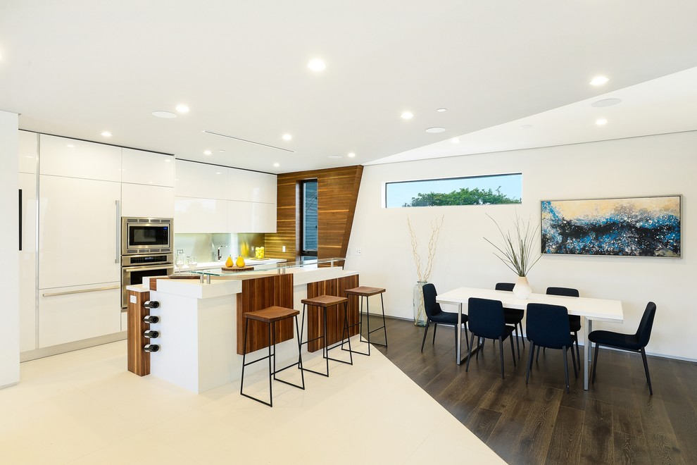 Zweizeilige Moderne Wohnküche mit flächenbündigen Schrankfronten, weißen Schränken, Küchengeräten aus Edelstahl, dunklem Holzboden und Kücheninsel in Los Angeles