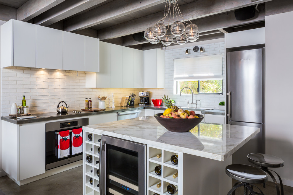 Trendy l-shaped kitchen photo in Los Angeles with flat-panel cabinets, white cabinets, white backsplash, subway tile backsplash and stainless steel appliances
