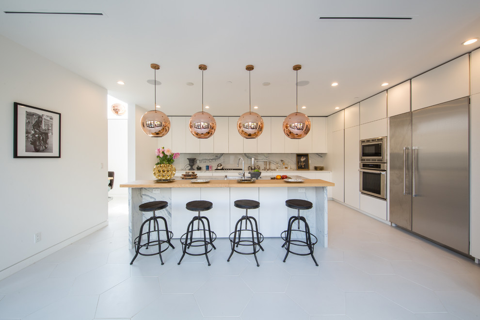Design ideas for a large contemporary l-shaped enclosed kitchen in Los Angeles with a submerged sink, flat-panel cabinets, white cabinets, wood worktops, white splashback, marble splashback, stainless steel appliances, porcelain flooring, an island and white floors.