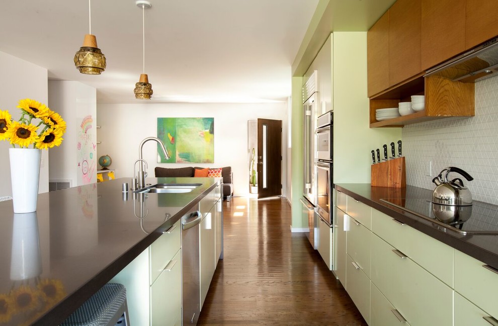 Bild på ett funkis brun brunt kök, med en undermonterad diskho, släta luckor, gröna skåp, grått stänkskydd, stänkskydd i keramik, rostfria vitvaror, mörkt trägolv, en köksö och brunt golv