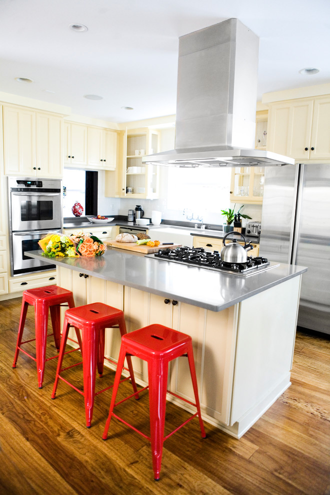Example of a transitional kitchen design in Los Angeles with a farmhouse sink, recessed-panel cabinets, yellow cabinets and stainless steel appliances