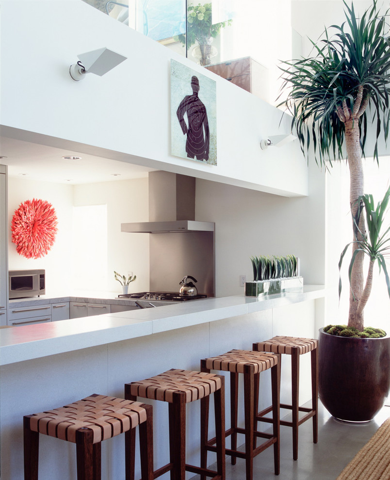 Geschlossene, Mittelgroße Moderne Küchenbar in L-Form mit Küchengeräten aus Edelstahl, weißen Schränken, Marmor-Arbeitsplatte, Küchenrückwand in Weiß, Betonboden und Kücheninsel in Los Angeles