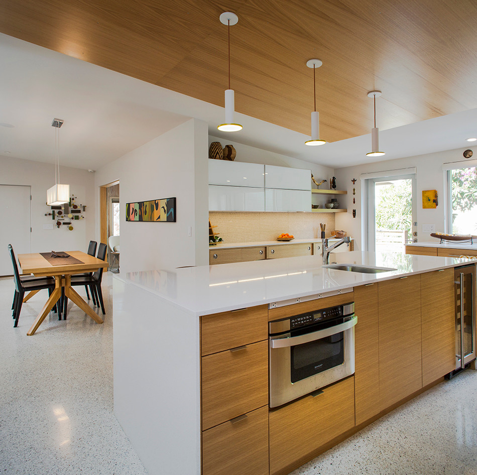 Example of a 1950s l-shaped concrete floor kitchen design in Tampa with flat-panel cabinets, light wood cabinets, gray backsplash, glass tile backsplash and an island