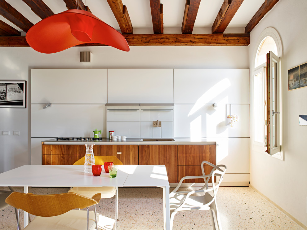 ヴェネツィアにある中くらいなコンテンポラリースタイルのおしゃれなキッチン (シングルシンク、フラットパネル扉のキャビネット、ステンレスカウンター、白いキッチンパネル、ガラス板のキッチンパネル) の写真