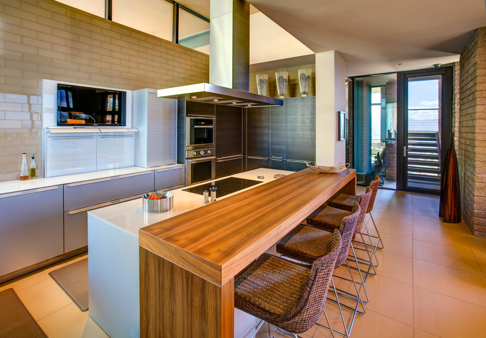 Пример оригинального дизайна: угловая кухня-гостиная среднего размера в стиле модернизм с плоскими фасадами, серыми фасадами, техникой из нержавеющей стали, полом из керамогранита, островом и бежевым полом