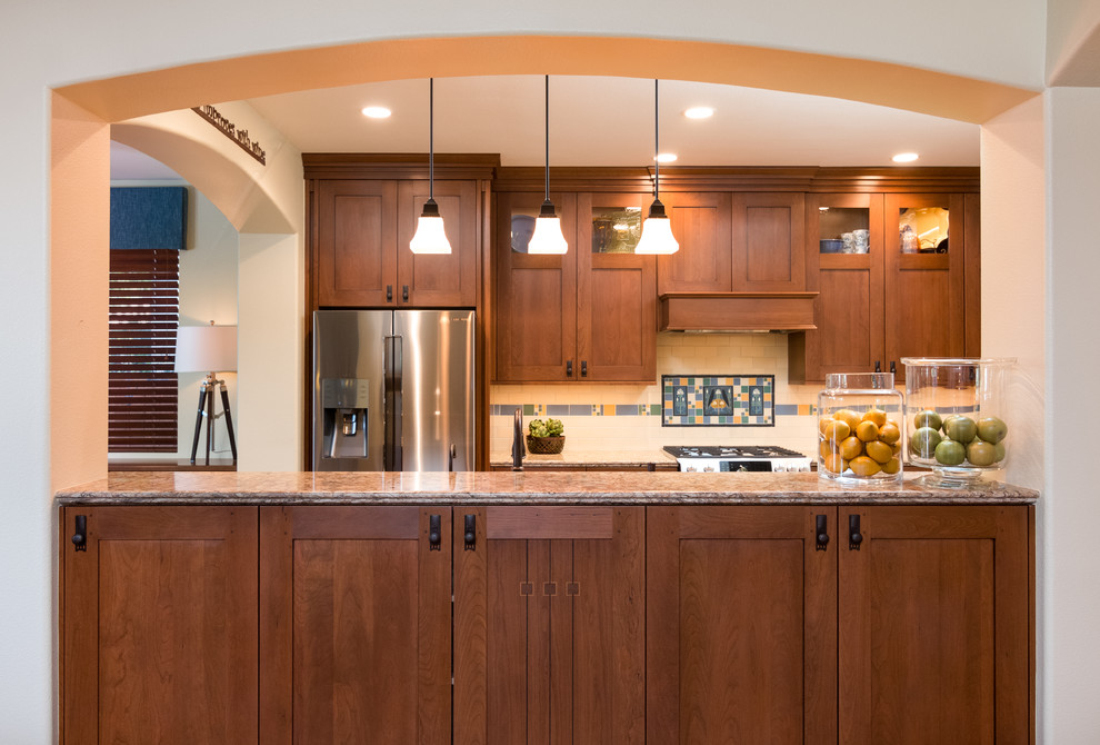 Arts and crafts eat-in kitchen photo in Los Angeles with shaker cabinets, medium tone wood cabinets, granite countertops, beige backsplash, ceramic backsplash, stainless steel appliances and an island