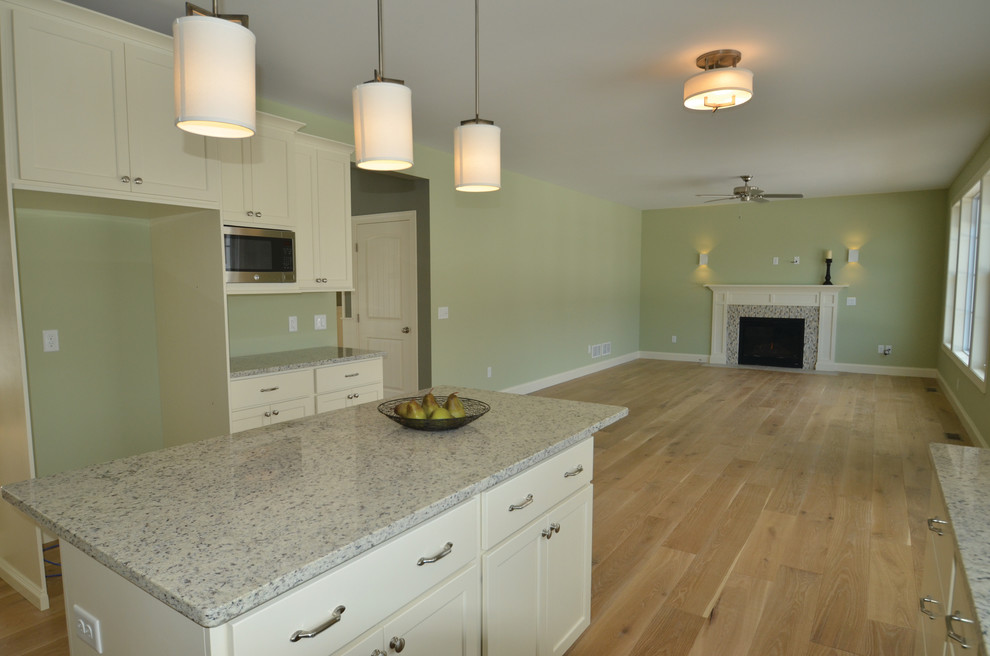 Modern inredning av ett stort kök och matrum, med luckor med infälld panel, vita skåp, granitbänkskiva, rostfria vitvaror, en köksö, en dubbel diskho och mellanmörkt trägolv