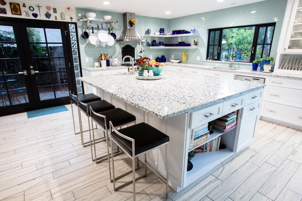 Exempel på ett avskilt, mellanstort maritimt l-kök, med en undermonterad diskho, skåp i shakerstil, vita skåp, bänkskiva i återvunnet glas, blått stänkskydd, stänkskydd i glaskakel, rostfria vitvaror, klinkergolv i porslin och en köksö