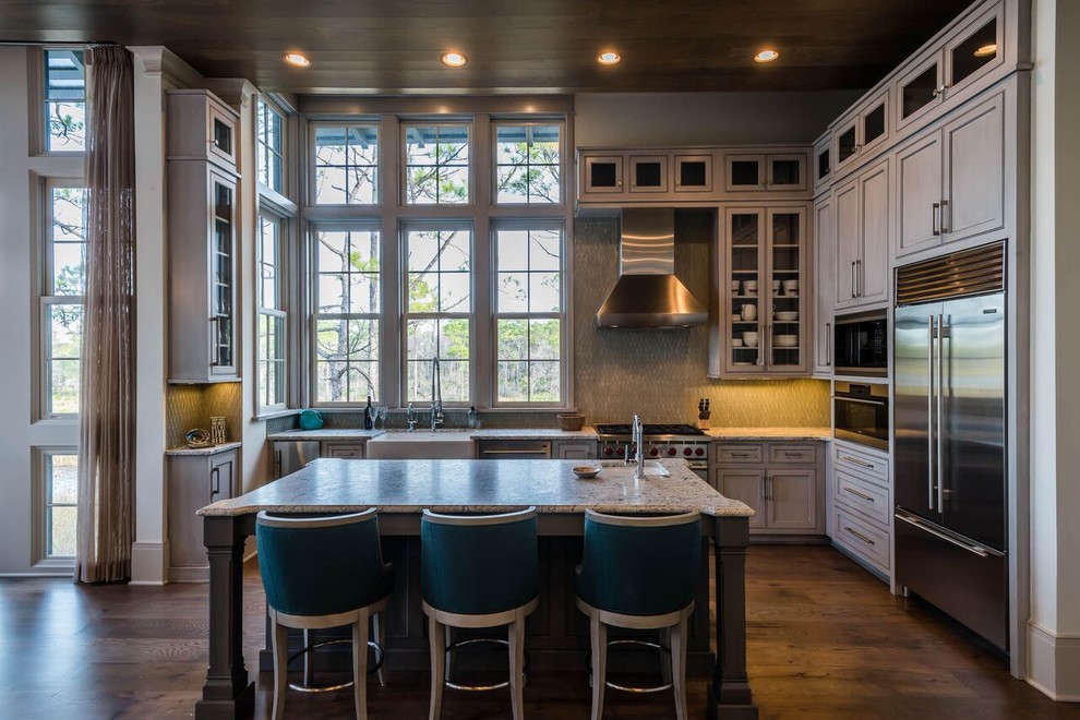 Example of a large classic u-shaped dark wood floor open concept kitchen design in Miami with a farmhouse sink, beaded inset cabinets, gray cabinets, granite countertops, gray backsplash, glass tile backsplash, stainless steel appliances and an island