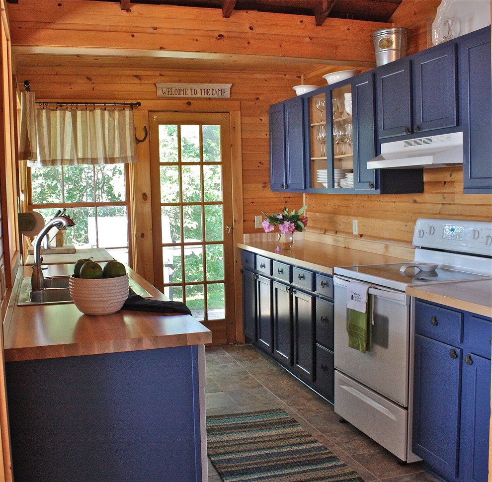 На фото: отдельная кухня в классическом стиле с белой техникой, деревянной столешницей, накладной мойкой, фасадами с утопленной филенкой и синими фасадами в частном доме