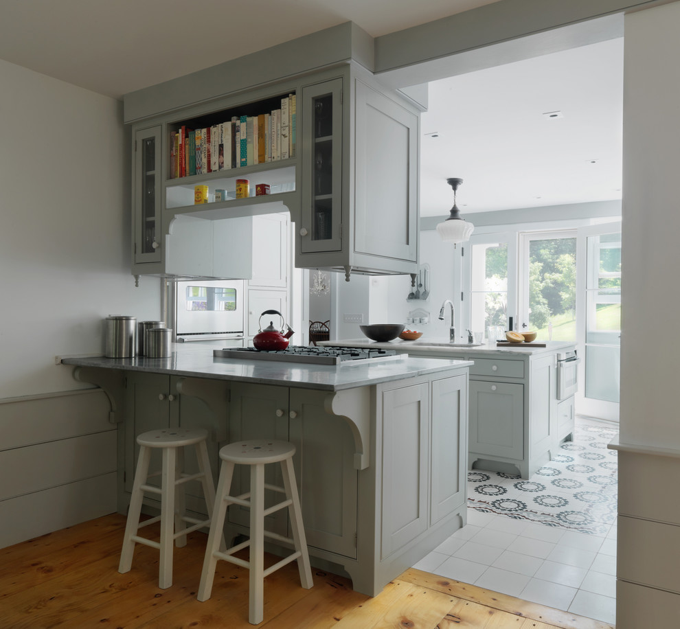 Cette image montre une cuisine rustique avec un placard avec porte à panneau encastré, des portes de placard grises et un électroménager en acier inoxydable.