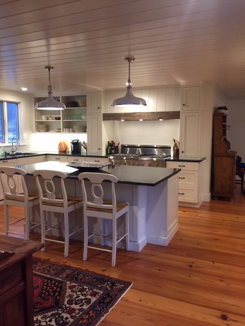 Inredning av ett lantligt avskilt, stort u-kök, med skåp i shakerstil, vita skåp, rostfria vitvaror, mellanmörkt trägolv, en köksö och brunt golv