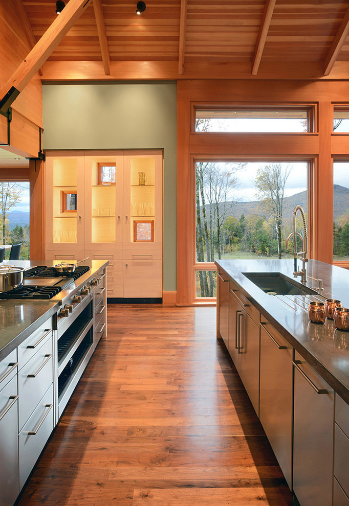 Rustik inredning av ett stort kök, med en enkel diskho, släta luckor, skåp i rostfritt stål, granitbänkskiva, rostfria vitvaror, en köksö och mellanmörkt trägolv