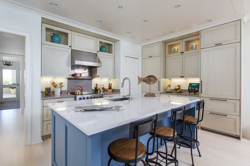 Beach style kitchen in DC Metro with a submerged sink, recessed-panel cabinets, light wood cabinets, stainless steel appliances, light hardwood flooring and an island.