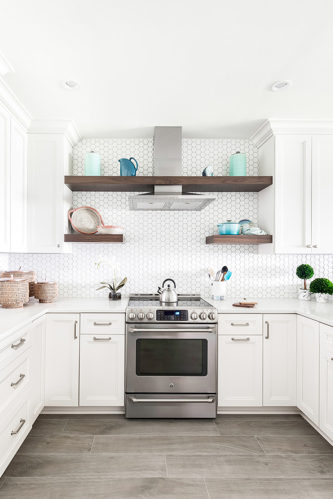 ビーチスタイルのおしゃれなコの字型キッチン (落し込みパネル扉のキャビネット、白いキャビネット、シルバーの調理設備、グレーの床、白いキッチンカウンター) の写真