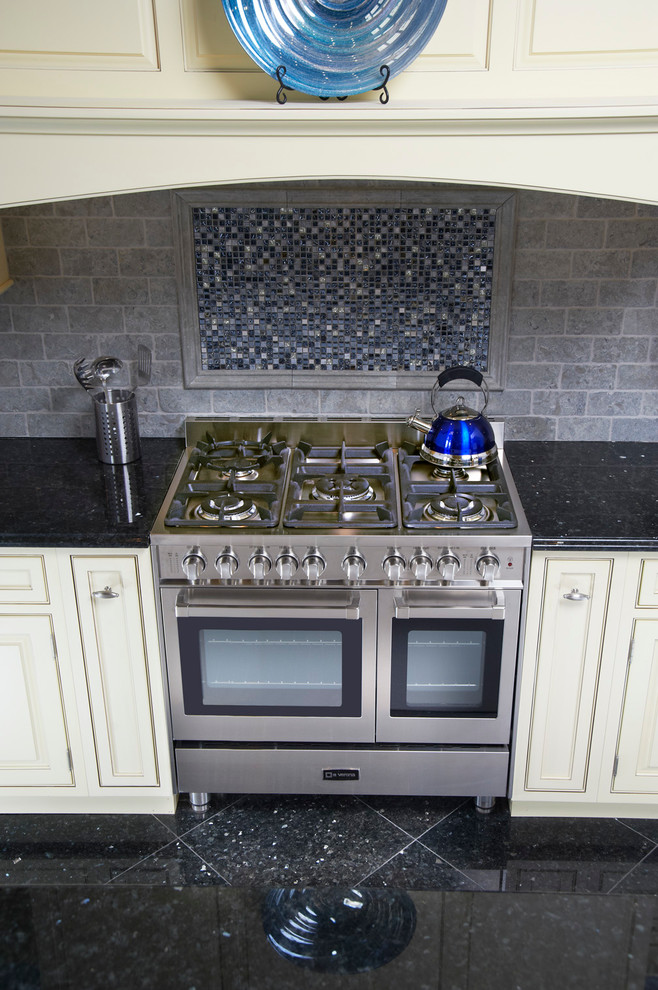 Esempio di una cucina chic con ante a filo, ante beige, paraspruzzi blu, paraspruzzi con piastrelle di vetro e elettrodomestici in acciaio inossidabile