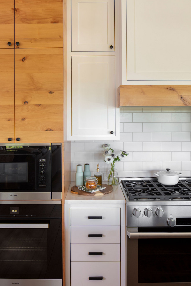 Landhaus Küche mit flächenbündigen Schrankfronten, hellbraunen Holzschränken und Küchengeräten aus Edelstahl in Austin