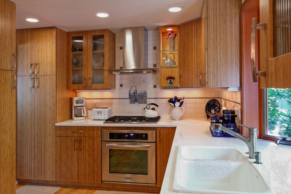 Example of a mid-sized u-shaped light wood floor eat-in kitchen design in Portland with a drop-in sink, flat-panel cabinets, medium tone wood cabinets, quartz countertops, white backsplash, subway tile backsplash, stainless steel appliances and no island