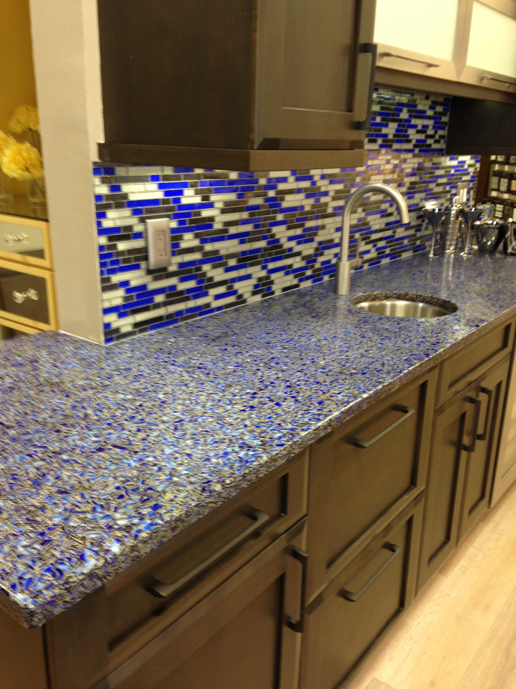На фото: кухня в современном стиле с врезной мойкой, столешницей из переработанного стекла, синим фартуком и фартуком из плитки мозаики