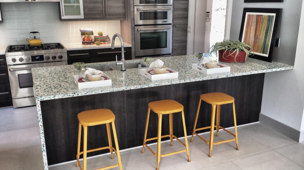 Moderne Küche mit dunklen Holzschränken, Arbeitsplatte aus Recyclingglas, Küchenrückwand in Weiß, Küchengeräten aus Edelstahl und Porzellan-Bodenfliesen in San Diego