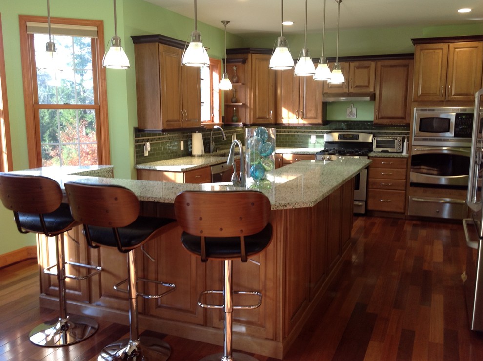 Large eclectic l-shaped medium tone wood floor eat-in kitchen photo in Boston with a single-bowl sink, raised-panel cabinets, medium tone wood cabinets, recycled glass countertops, stainless steel appliances and an island
