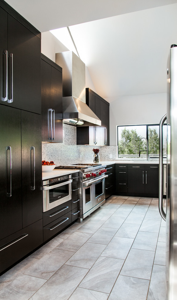 Modern inredning av ett kök, med en undermonterad diskho, släta luckor, bruna skåp, bänkskiva i kvartsit, vitt stänkskydd, stänkskydd i stenkakel och rostfria vitvaror