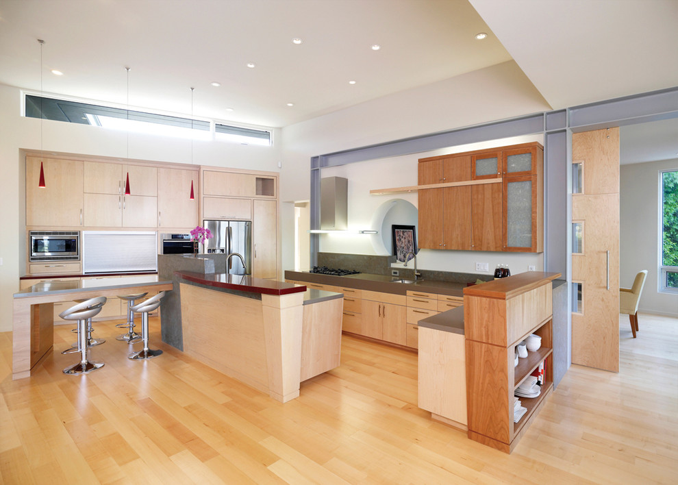 Moderne Küche mit flächenbündigen Schrankfronten, hellen Holzschränken und Küchengeräten aus Edelstahl in Los Angeles