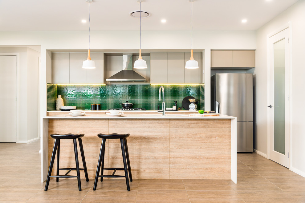 Zweizeilige Moderne Küche mit flächenbündigen Schrankfronten, hellen Holzschränken, Küchenrückwand in Grün, Rückwand aus Mosaikfliesen, Küchengeräten aus Edelstahl, Kücheninsel, beigem Boden und weißer Arbeitsplatte in Sydney