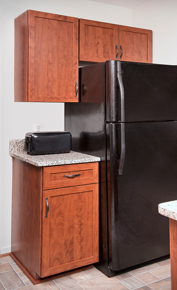 Cette image montre une cuisine chalet en U et bois brun avec un évier encastré, un placard avec porte à panneau encastré, un plan de travail en stratifié, un électroménager noir et îlot.
