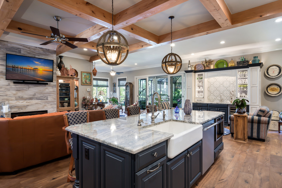 Inspiration for a transitional light wood floor eat-in kitchen remodel in Jacksonville with a farmhouse sink, raised-panel cabinets, blue cabinets, granite countertops, brown backsplash, ceramic backsplash, stainless steel appliances and an island