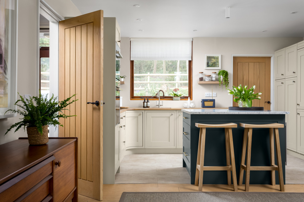 Medium sized farmhouse l-shaped open plan kitchen in Gloucestershire with recessed-panel cabinets, beige cabinets, wood worktops, an island, beige floors, brown worktops and a single-bowl sink.