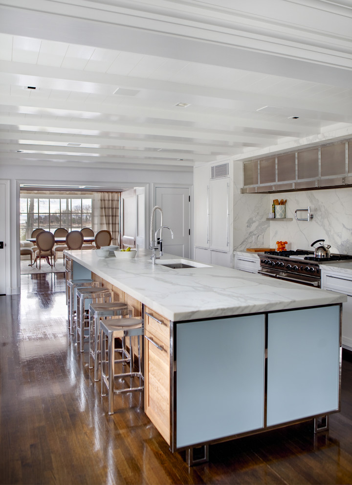Modern inredning av ett stort linjärt kök med öppen planlösning, med en undermonterad diskho, skåp i shakerstil, vita skåp, vitt stänkskydd, marmorbänkskiva, stänkskydd i sten, rostfria vitvaror, mörkt trägolv, en köksö och brunt golv