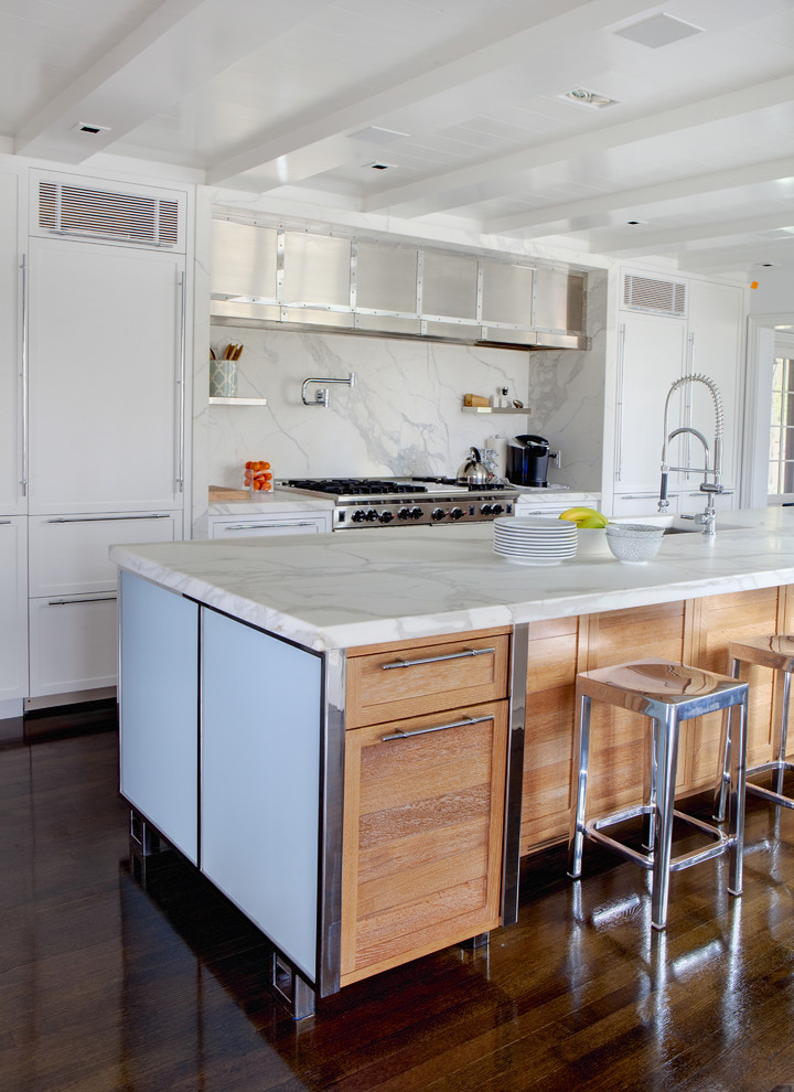 Inredning av ett modernt stort linjärt kök med öppen planlösning, med skåp i shakerstil, vita skåp, vitt stänkskydd, en undermonterad diskho, marmorbänkskiva, stänkskydd i sten, rostfria vitvaror, mörkt trägolv, en köksö och brunt golv