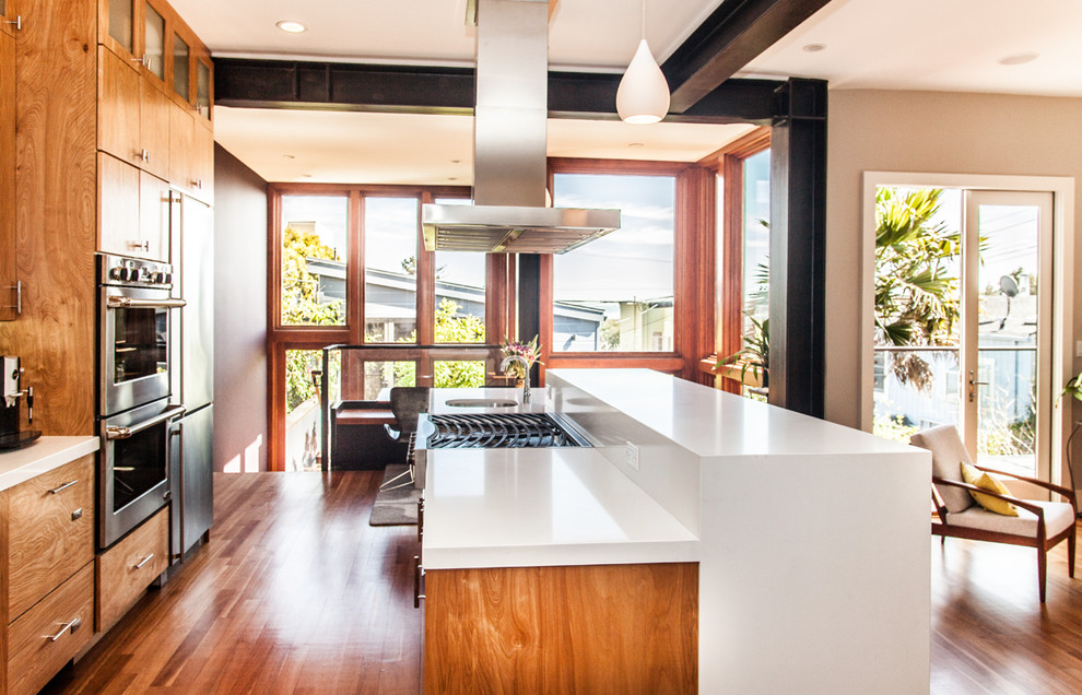 Свежая идея для дизайна: кухня в стиле модернизм с плоскими фасадами, фасадами цвета дерева среднего тона и техникой из нержавеющей стали - отличное фото интерьера