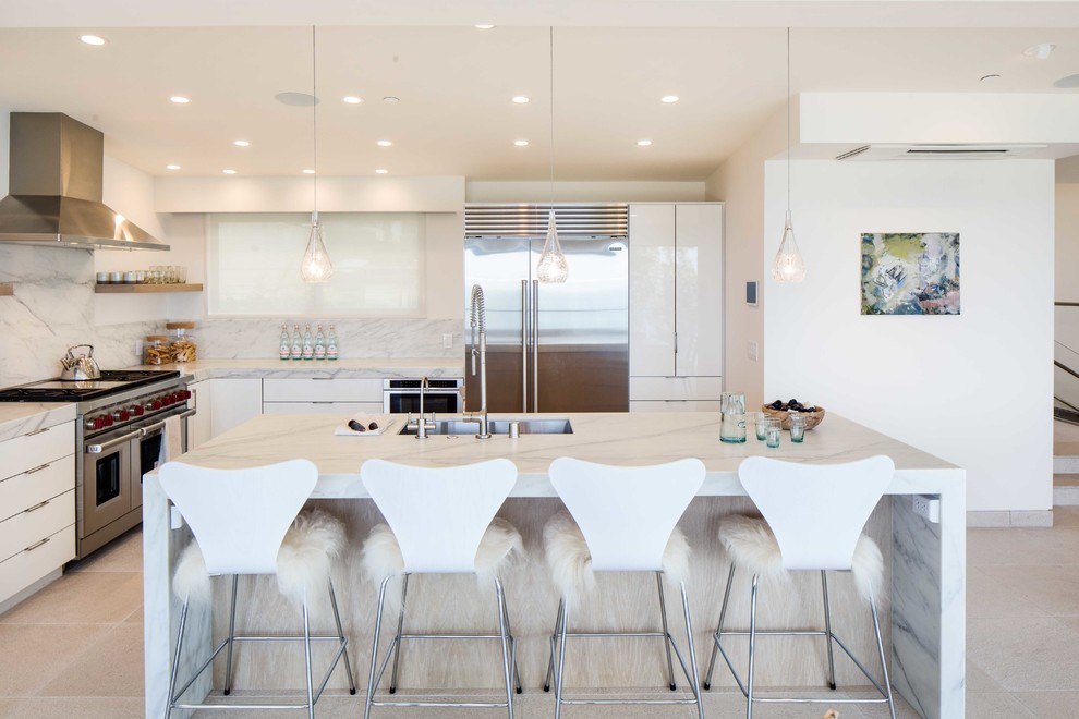 Moderne Küche in L-Form mit Unterbauwaschbecken, flächenbündigen Schrankfronten, weißen Schränken, Küchenrückwand in Weiß, Küchengeräten aus Edelstahl und Kücheninsel in Orange County