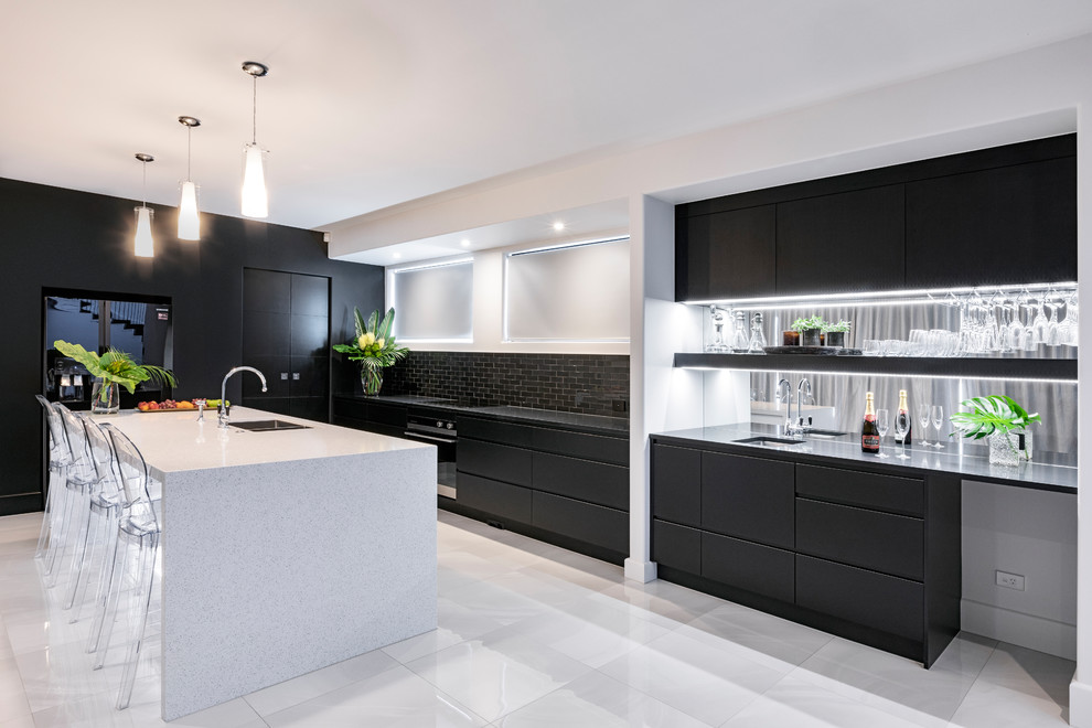 Cette photo montre une cuisine tendance en L avec un placard à porte plane, des portes de placard noires, un électroménager noir, îlot, un sol gris et plan de travail noir.