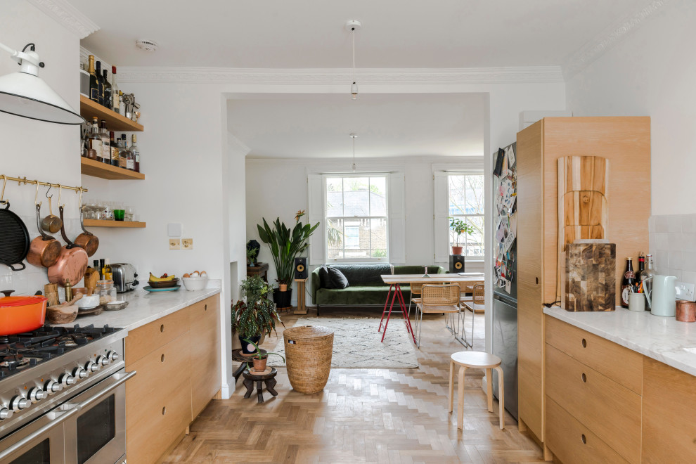 Inspiration for an eclectic galley kitchen in London with flat-panel cabinets, medium wood cabinets, white splashback, light hardwood flooring, no island, beige floors and white worktops.