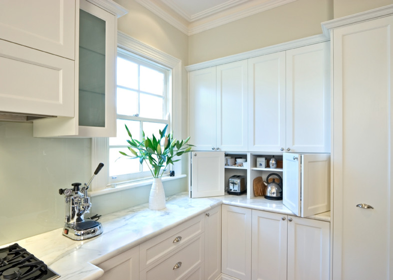 Cette image montre une grande cuisine traditionnelle avec un placard à porte shaker, plan de travail en marbre et une crédence en feuille de verre.