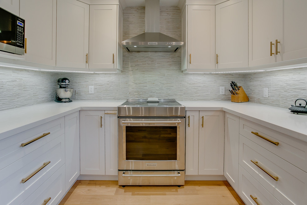 Exempel på ett mellanstort klassiskt vit vitt kök, med en undermonterad diskho, skåp i shakerstil, vita skåp, bänkskiva i kvarts, flerfärgad stänkskydd, stänkskydd i porslinskakel, rostfria vitvaror, mellanmörkt trägolv och en halv köksö