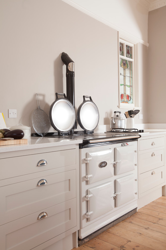 This is an example of a traditional single-wall open plan kitchen in Cardiff with a submerged sink, shaker cabinets, white cabinets, quartz worktops, coloured appliances and an island.